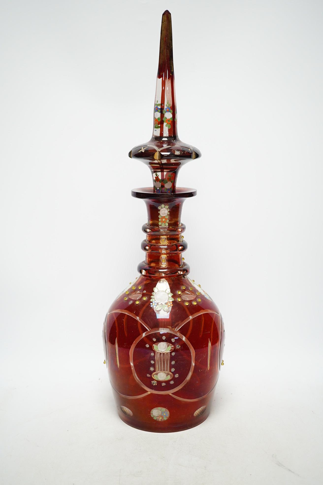 An early 20th century Bohemian overlaid and painted ruby glass decanter, 51cm. Condition - fair